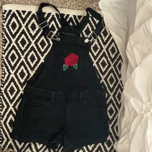 Black denim overall shorts with red floral detail.